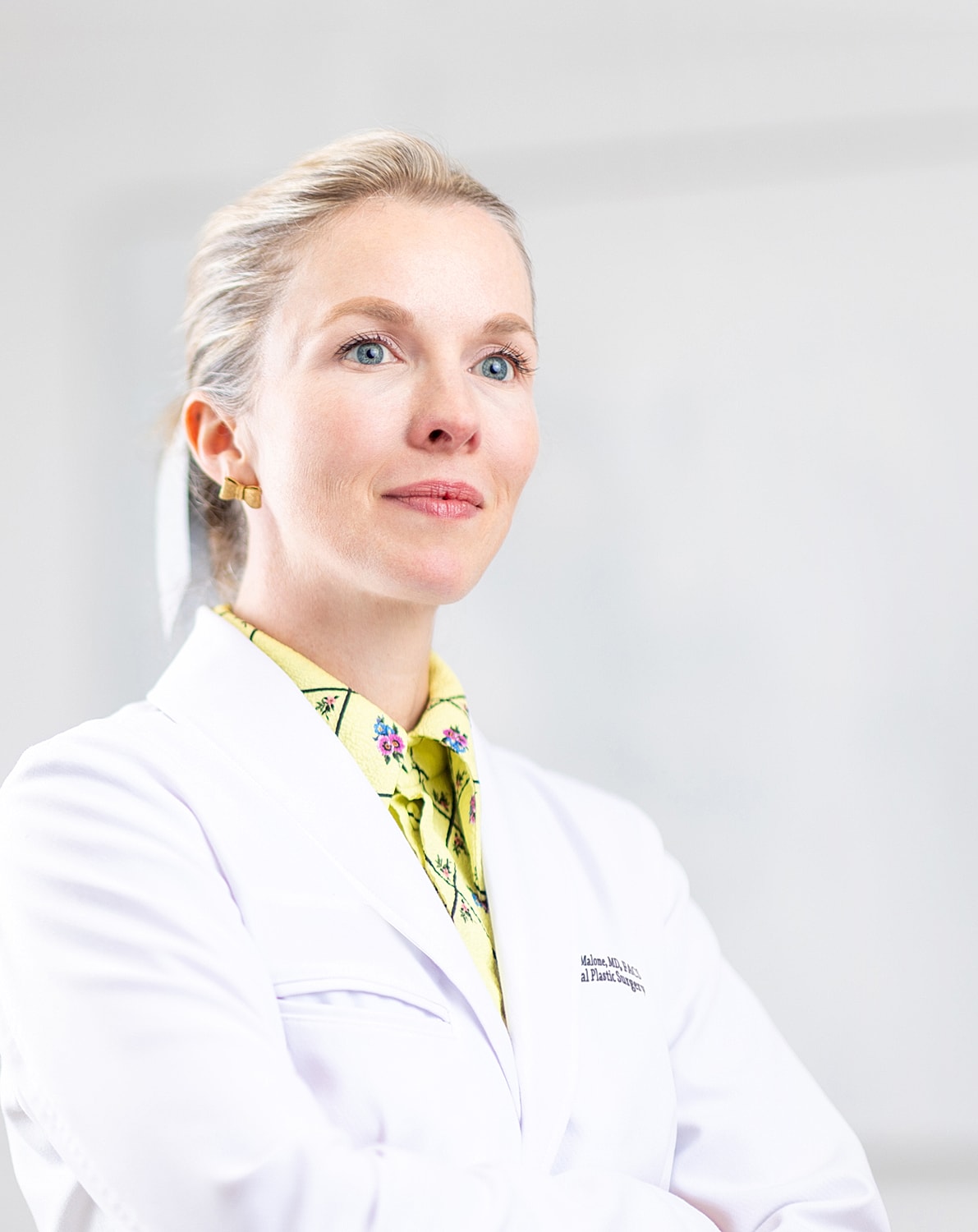 Female doctor in a white lab coat, confident expression.