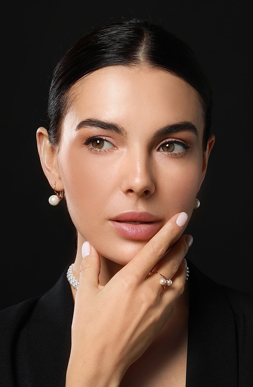 Woman with pearl jewelry and neutral makeup.