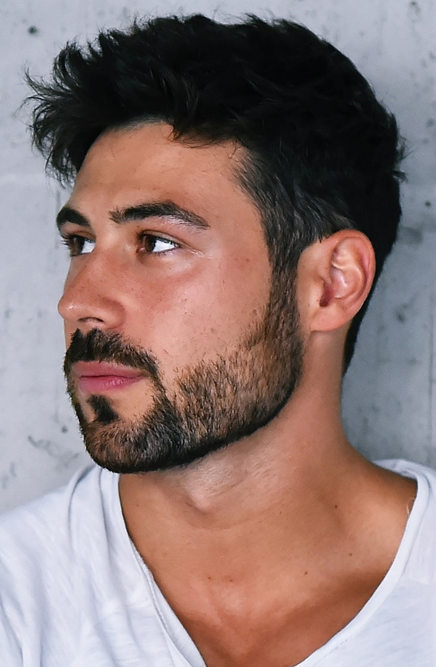 Man with beard looking thoughtfully to the side.