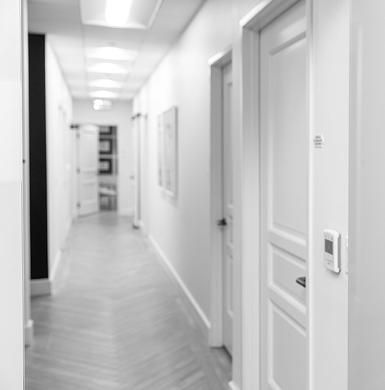 Empty corridor with closed doors and white walls