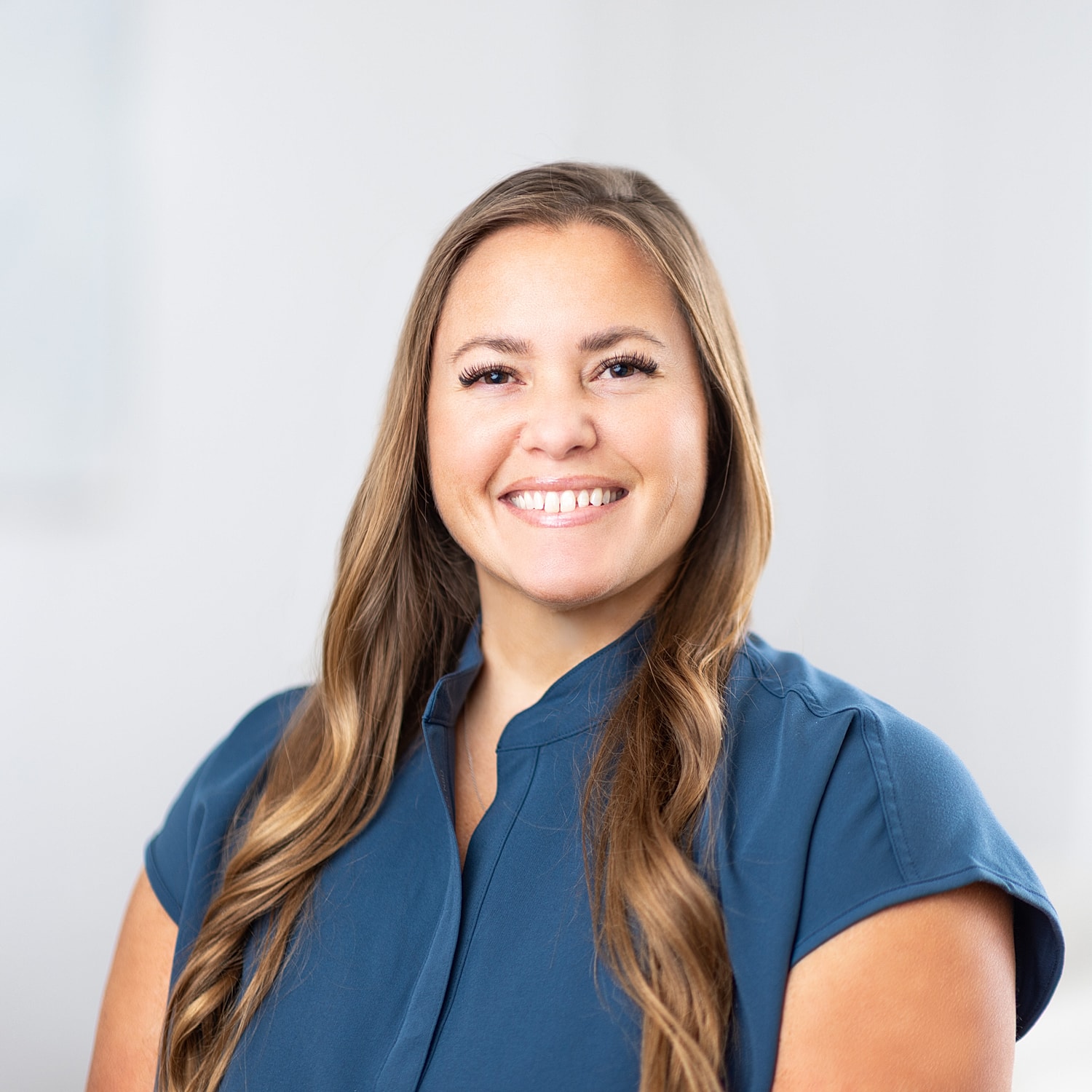 Smiling woman in blue top with long hair.