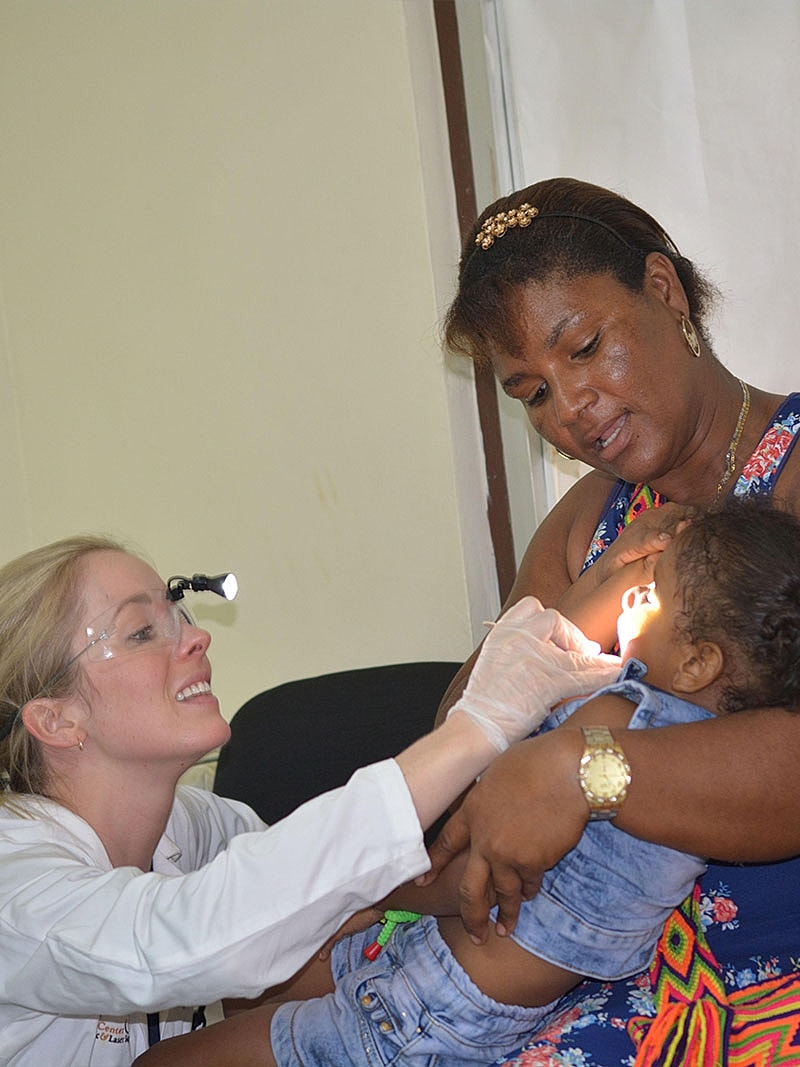 Dr Malone Facial Plastic Surgeon San DiegoDentist examining child's teeth with mother's support.