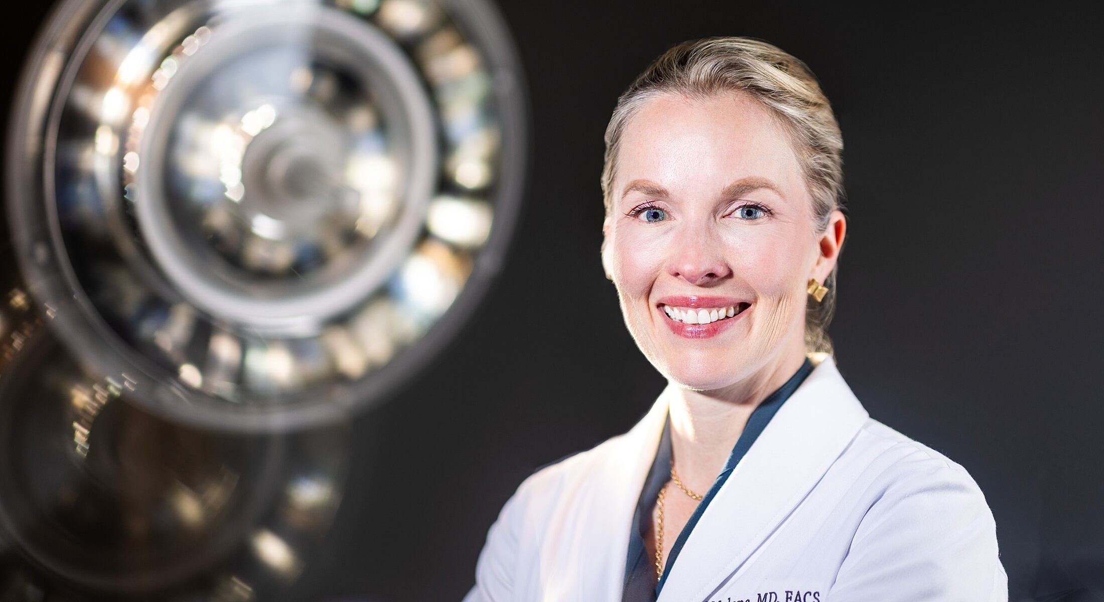 Smiling doctor in surgical environment with spotlight.