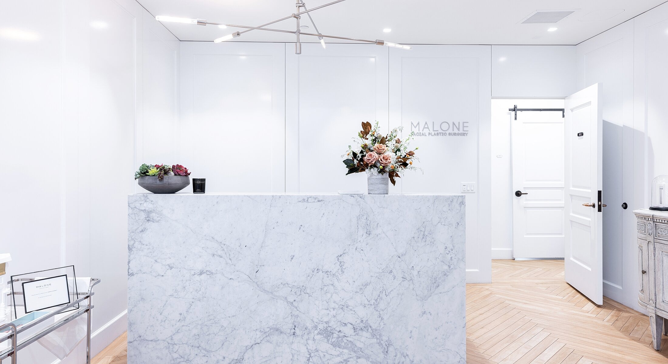 Modern reception area with marble counter and flowers.