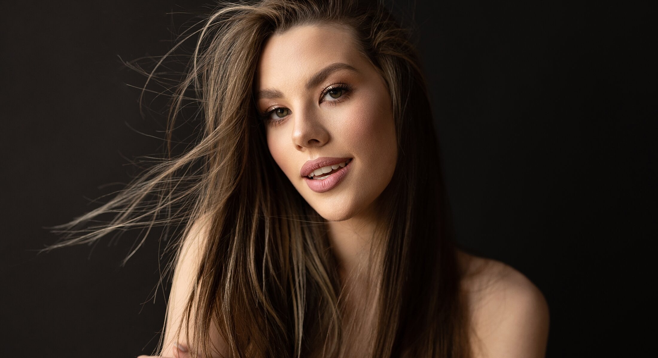 Woman with long hair against dark background.