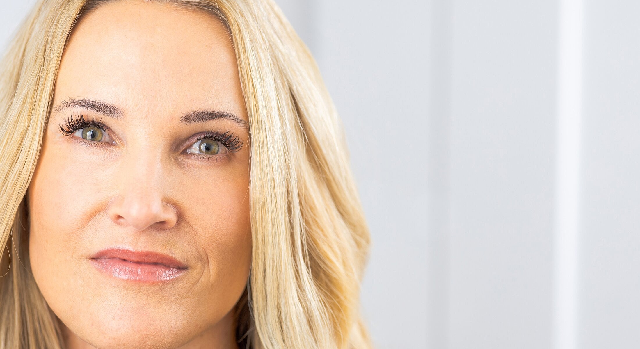Close-up of a smiling woman with blonde hair.