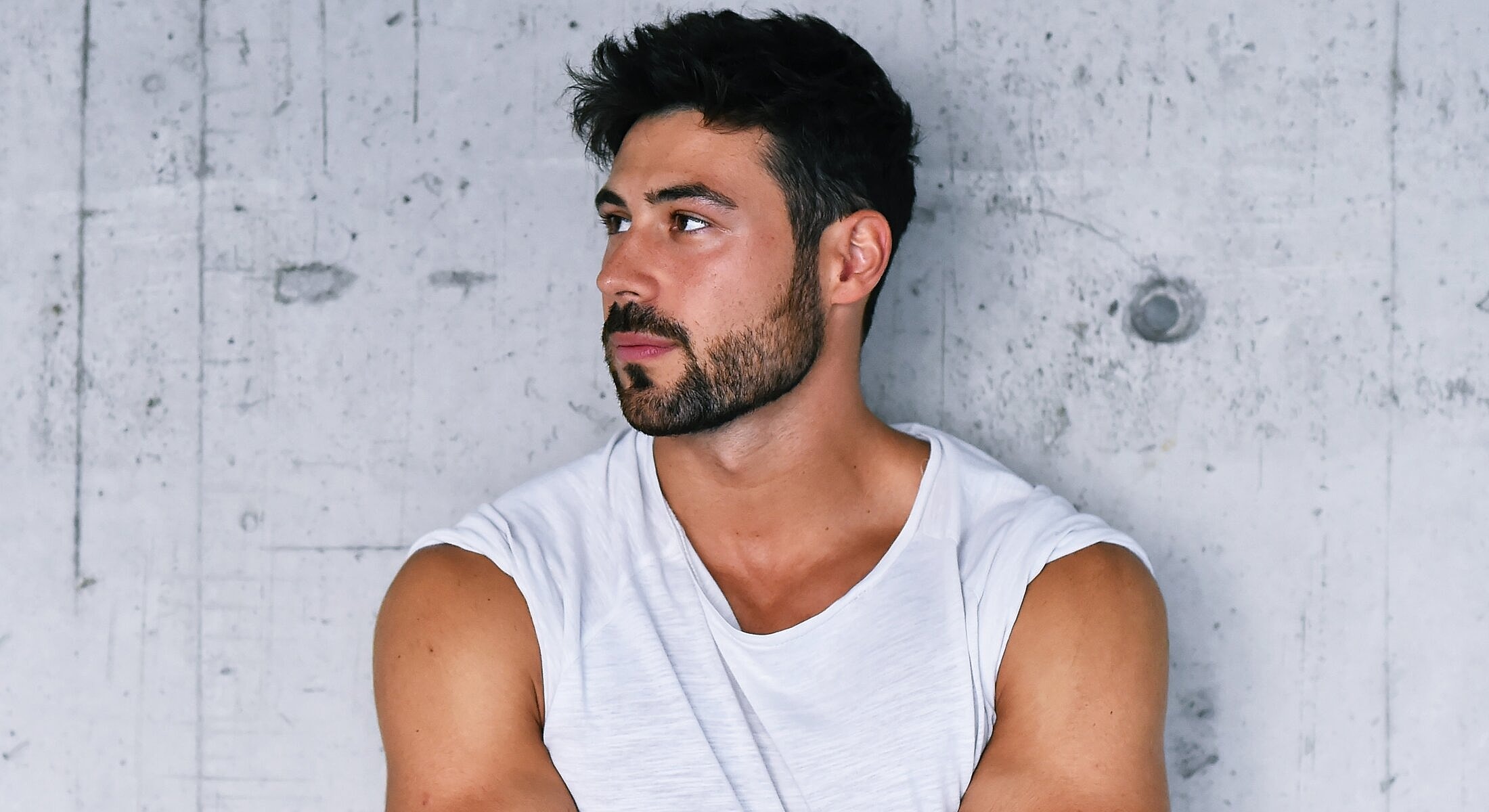 Man in white shirt against concrete background.