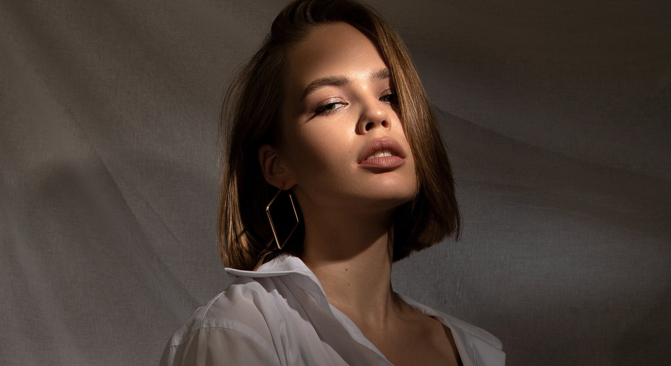Model with short hair and elegant earrings.